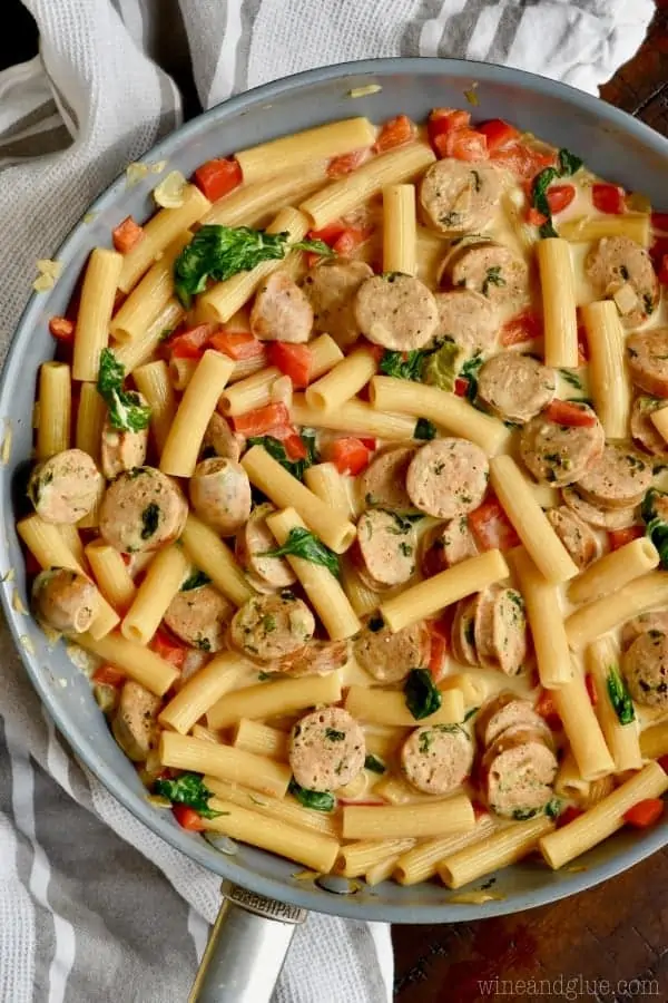 In a skillet, the Sausage Pasta Skillet shows the different rainbow colors from the sausage, pasta, spinach, red peppers, and tomatoes. 