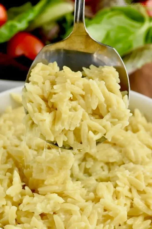 A spoon is digging out some of the Cheesy Orzo showing some cheese pull