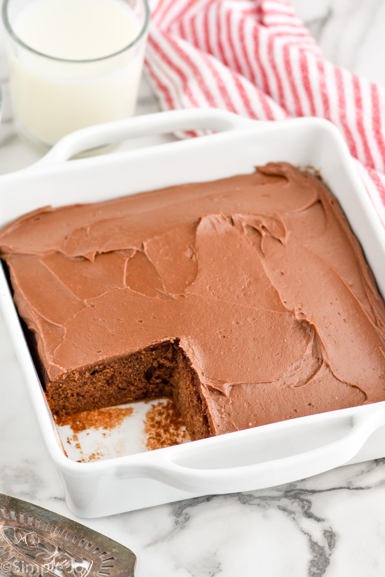 square baking dish with homemade chocolate cake with a piece missing
