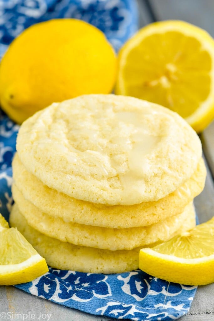 Close up photo of a stack of Lemon Sugar Cookies surrounded by lemons.