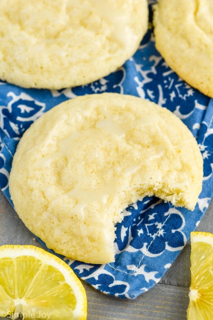 Overhead photo of Lemon Sugar Cookie with a bite taken out of it. Lemon slices beside cookies.