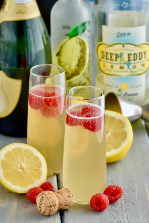 In a champagne fluke, the Lemon Champagne Cocktail has a yellow tint and topped with raspberries