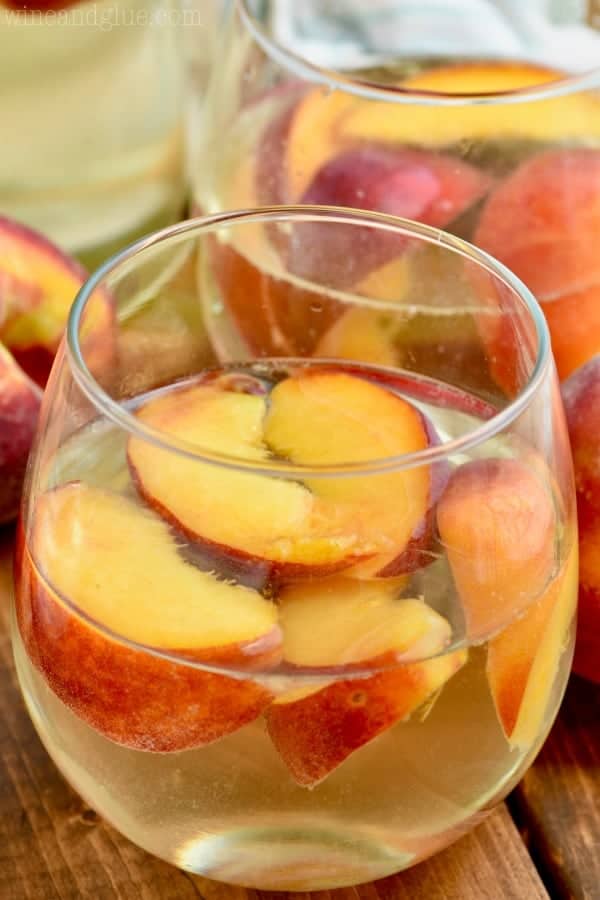 wine glass filled with peach sangria recipe including fresh peaches