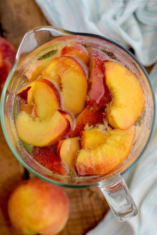 overhead view of pitcher of peach sangria recipe with fresh peaches floating in it