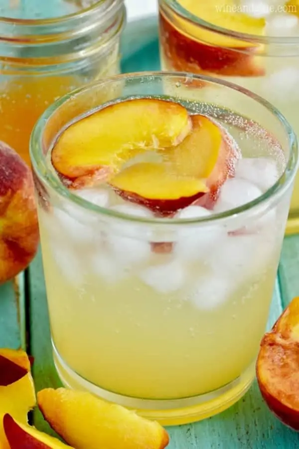 In a clear glass, the Peach Vodka Smash has two sliced peaches with ice. 