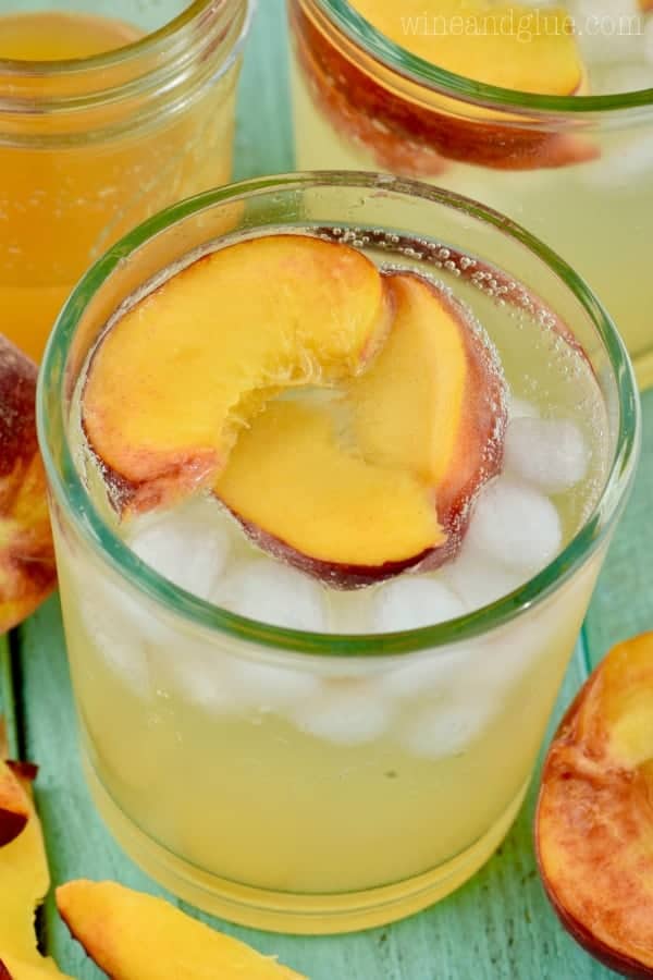 An overhead photo of the glass of the Peach Vodka Smash with three slices of peach and ice cubes. 