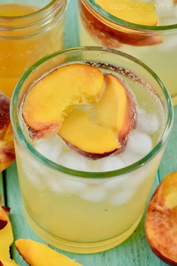 An overhead photo of the glass of the Peach Vodka Smash with three slices of peach and ice cubes. 