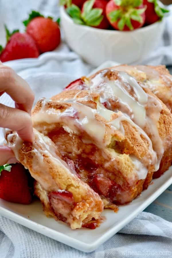 Someone is pulling apart the Strawberry and Cream Pull Apart Bread showing the gooey inside from the strawberries. 