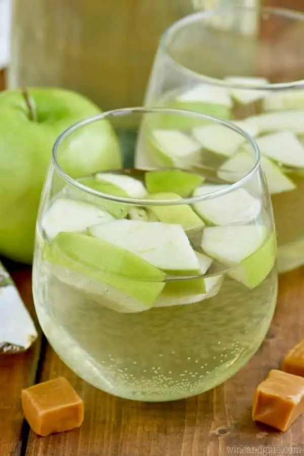 In a glass, the Caramel Apple Sangria has a dash of green color with sliced green apples. 