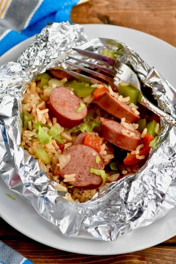 On a white plate, the Jambalaya Foil Packet  has cut sausages, peppers, lettuce, and rice.