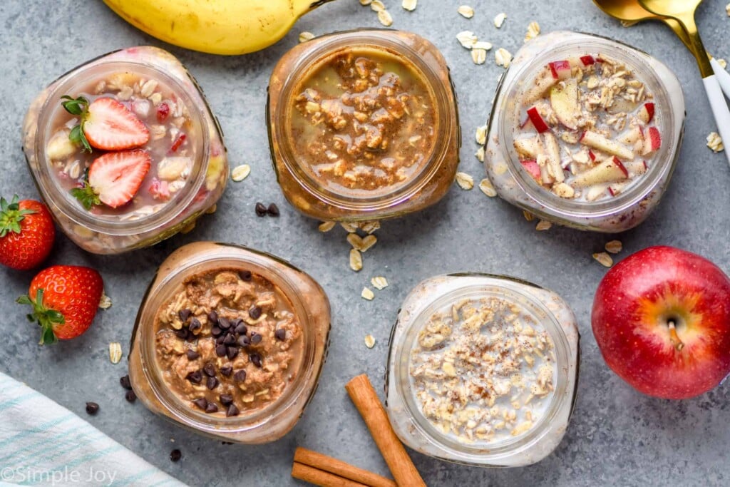 overhead view of five mason jars filled with different flavors of overnight oats