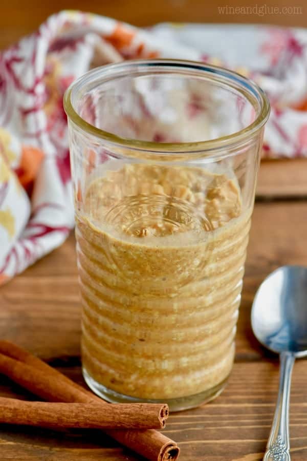 The Pumpkin Pie Overnight Oats are in a clear glass and has a beautiful orange brown color