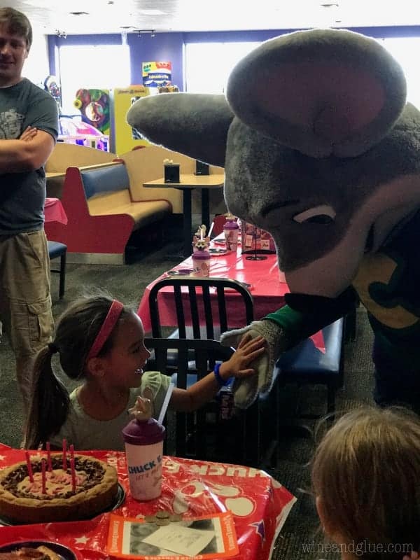A little girl is giving Chuck E. Cheese a high-five