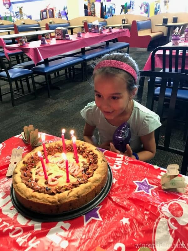 A little girl about to blow the candles on the cookie cake. 