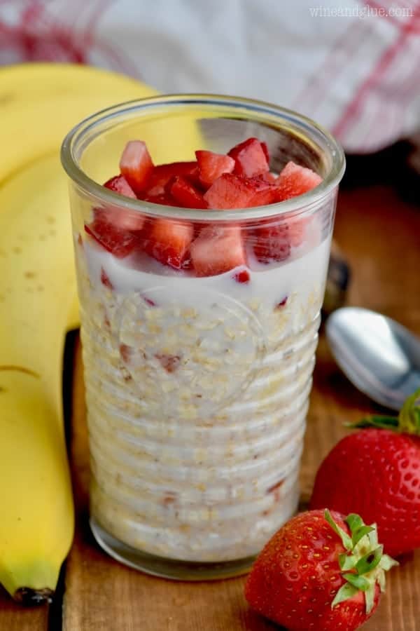 In a clear glass, the Strawberry Banana Overnight Oats is topped with sliced strawberries. 