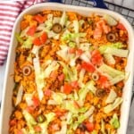 Pinterest graphic of overhead of baked taco casserole garnished with olives, tomatoes, and iceberg lettuce that says "the best baked taco casserole simplejoy.com"