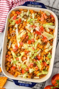 overhead of baked taco casserole garnished with olives, tomatoes, and iceberg lettuce