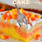 piece of candy corn poke cake, the colors of candy corn with cool whip on top and topped with candy corn