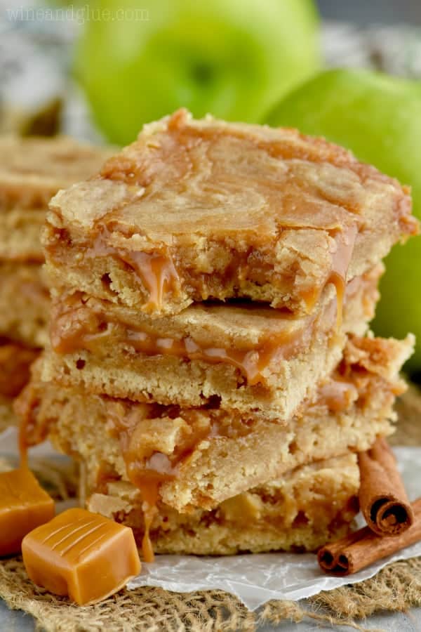 The Caramel Apple Sugar Cookie Bars are stacked on top of each other showing the caramel oozing out of the golden brown cookie bar. 
