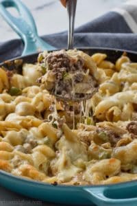 skillet full of phlily cheese steak casserole with spoonful being pulled out