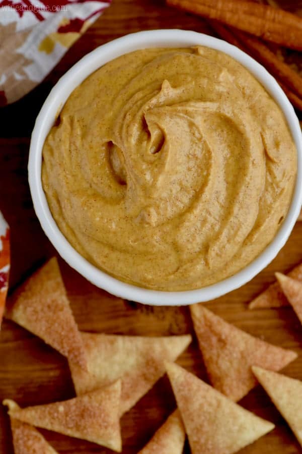 Overhead photo of a white bowl filled with the Pumpkin Pie Dip and surrounded by the triangular Cinnamon Sugar Pie Crust Dippers