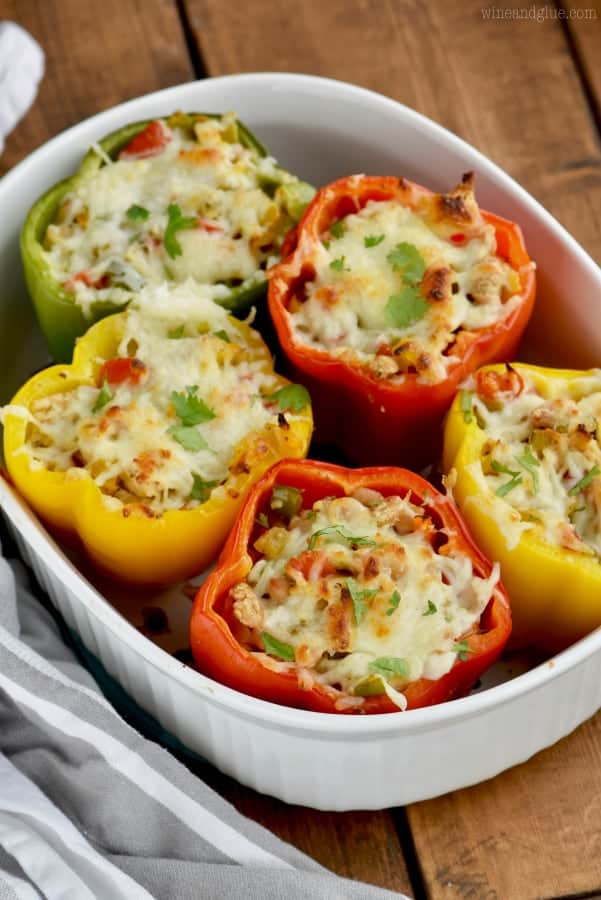 In a casserole dish, the White Chicken Chili Stuffed Peppers are topped with a beautiful cheese crust and parsley 