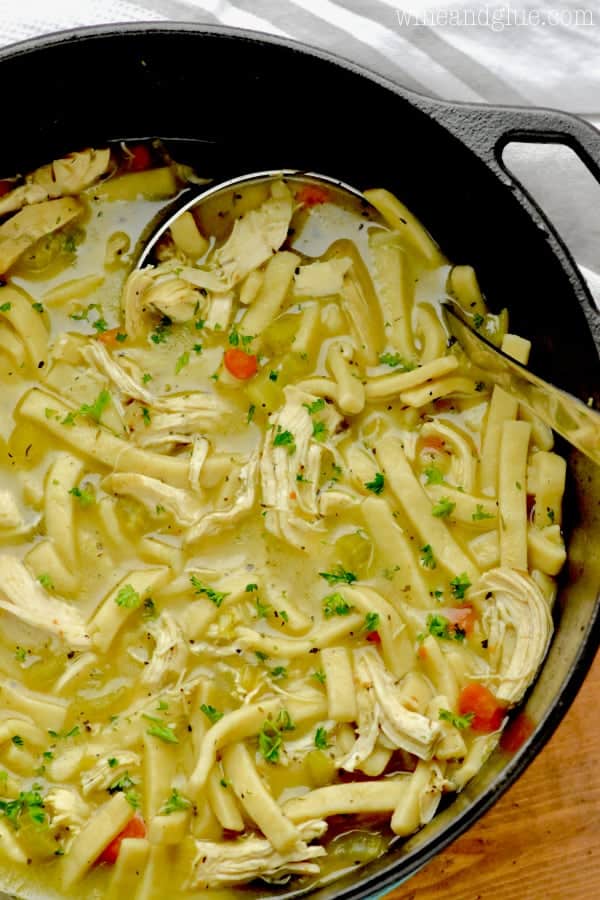 In a cast iron pot, the Homemade Chicken Noodle Soup is a beautiful golden brown color with a pop of orange from the carrots. 