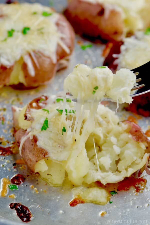 The Italian Roasted Smashed potatoes are on aluminium foil with melted cheese and minced parsley. 
