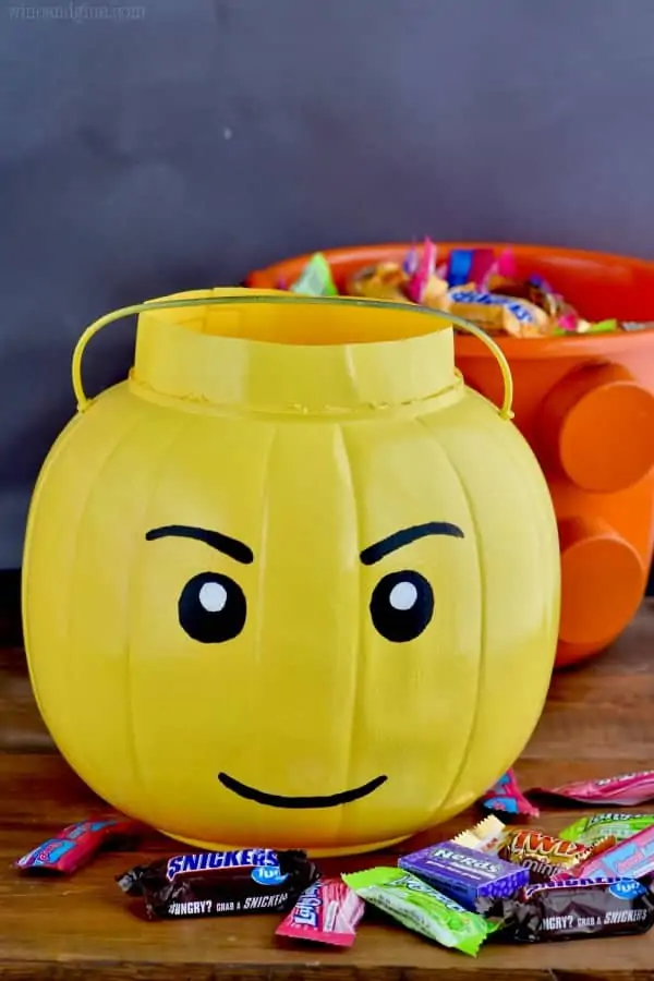 Two Halloween Treat Buckets: one shaped as a lego man head and the other into a lego piece. 