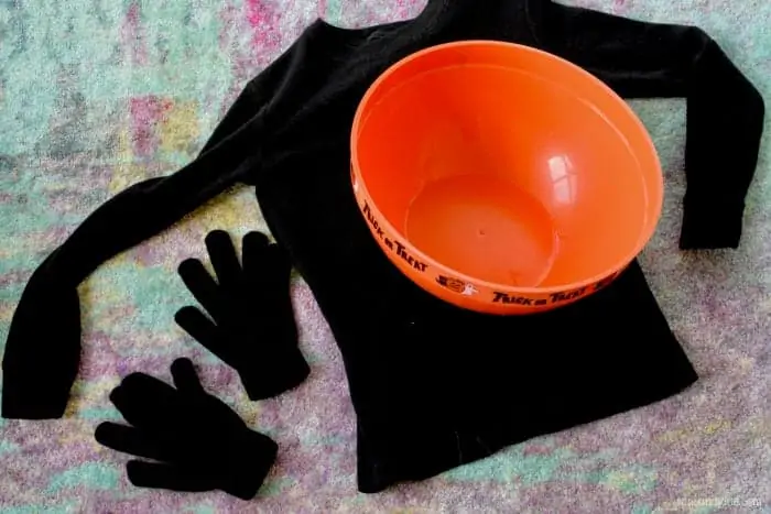 Two black gloves, a long black sleeves shirt, and a candy bowl are in the photo