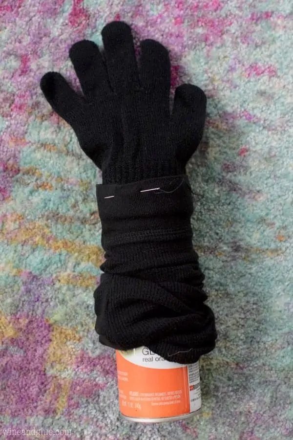 A sleeve from the black longed sleeved shirt has a black glove attached to it and a can on the other side. 