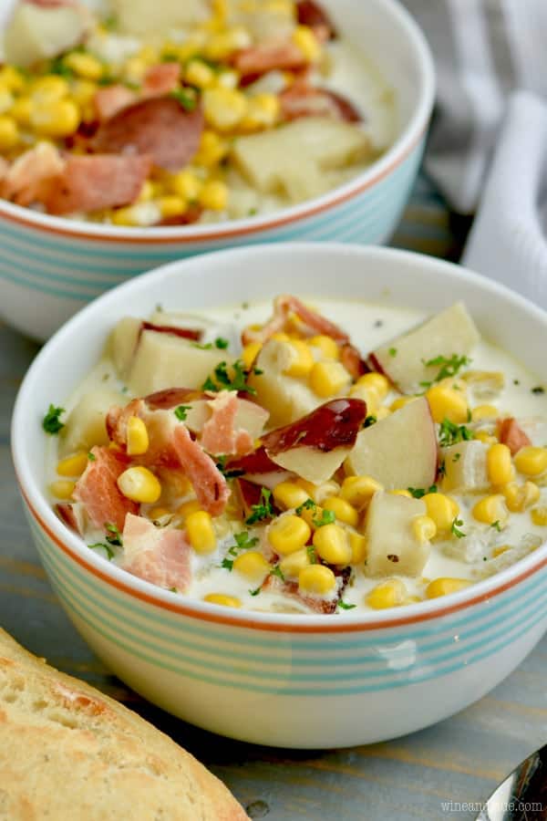 The Slow Cooker Bacon Potato Corn Chowder has a creamy white base topped with bacon pieces, cubed potato, corn, and parsley. 