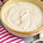 Pinterest graphic for horseradish sauce. Image shows bowl of homemade horseradish sauce with platter of prime rib in background for serving. Text says "horseradish sauce simplejoy.com"