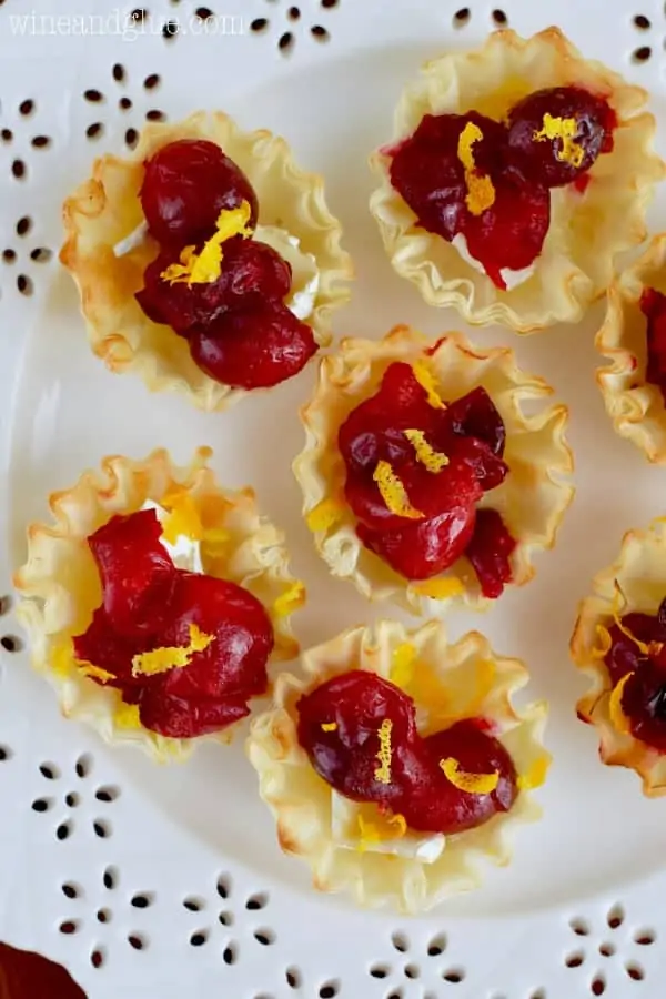 On a white plate, the Cranberry Brie Bites are topped with orange zest. 