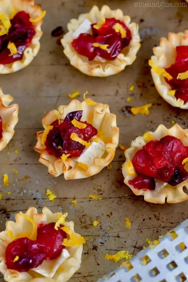 An overhead photo of the Cranberry Brie Bites lined up with orange zest topping them. The filo shells has a golden brown color. 
