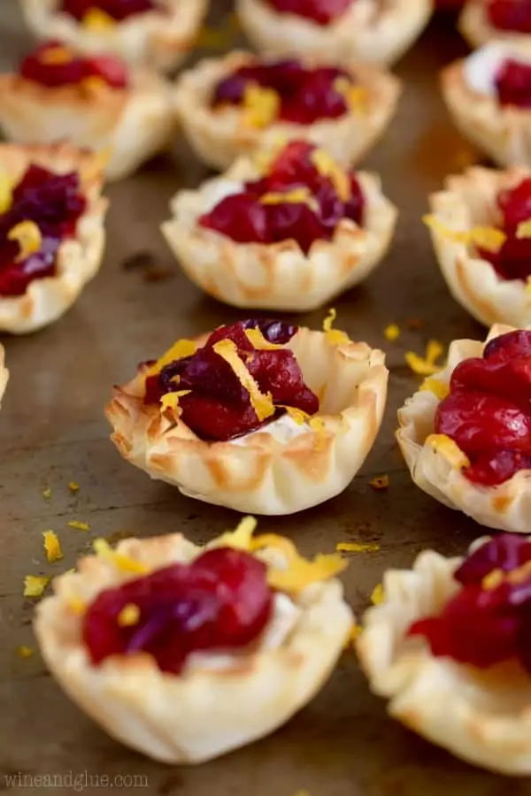 Lined up on a backing sheet, the Cranberry Brie Bites are topped with some Orange Zest. 