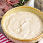 bowl of homemade horseradish sauce with platter of prime rib in background