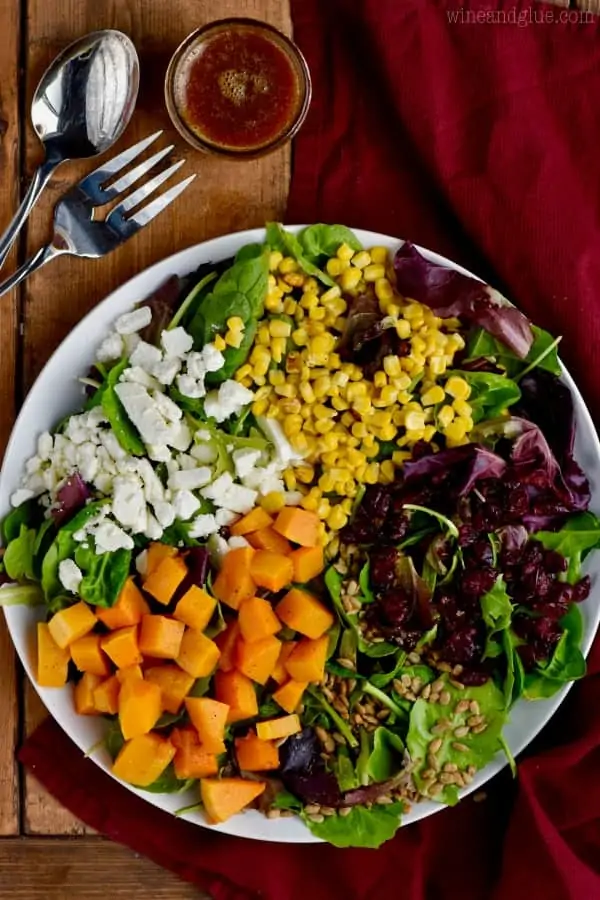 An overhead photo of the beautiful colorful Fall Salad which has feta cheese, butternut squash, cranberries, corn, greens, and sunflower seeds. 