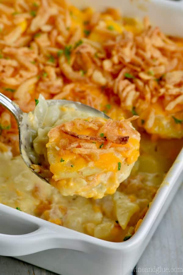 A scoopful of The Best Scalloped Potatoes coming out of the casserole dish. 