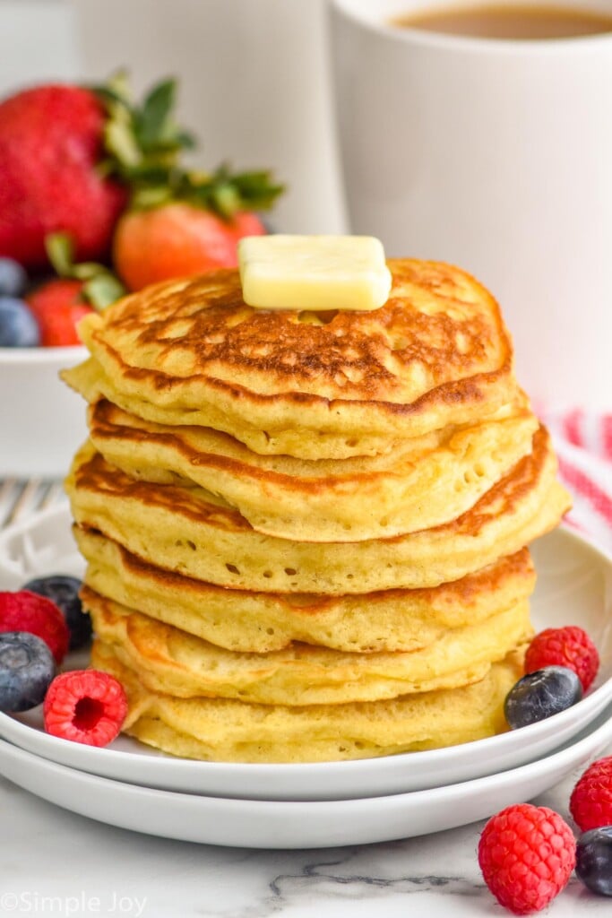 stack of six buttermilk pancakes with a pad of butter on top