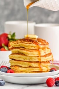 stack of buttermilk pancakes with syrup being drizzled over them