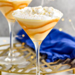 two martini glasses lined with caramel sauce with an eggnog martini, topped with whipped cream - 7