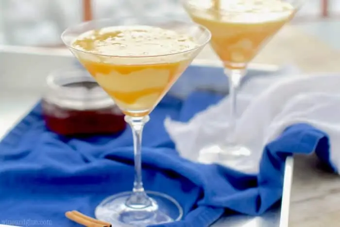 Two glass Eggnog Martinis with caramel dripping on the sides in the inside. 