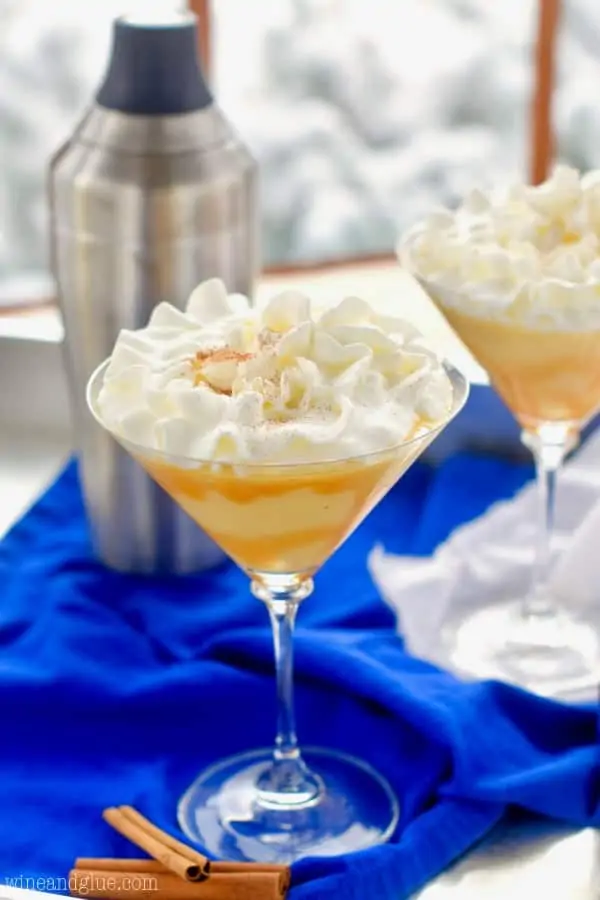 A glass of the Eggnog Martini with whip cream on top and caramel dripping on the sides. 