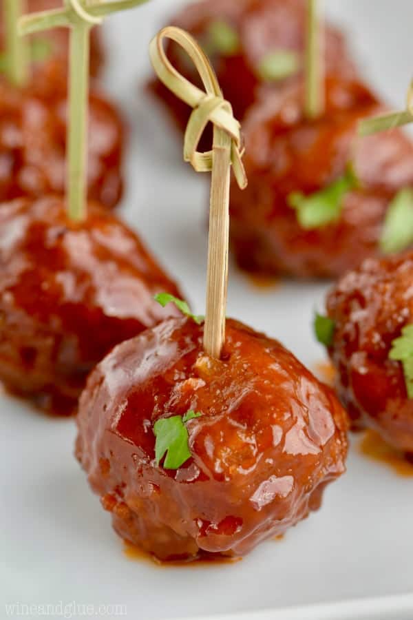 The Honey BBQ Instant Pot Cocktail Meatballs are on a toothpick lined up on a white plate. 