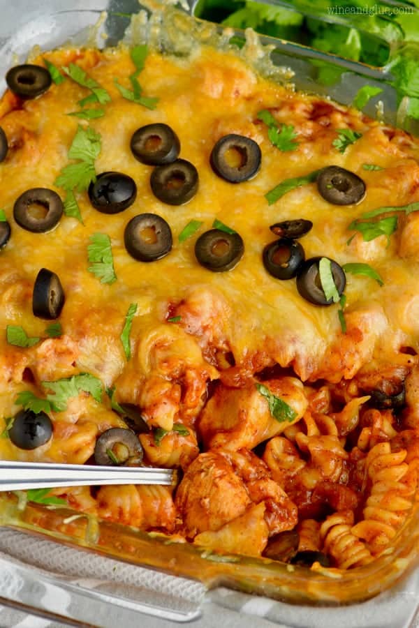 In a casserole dish, the Instant Pot Chicken Enchilada Casserole is topped with melted cheese, olives, and parsley. 