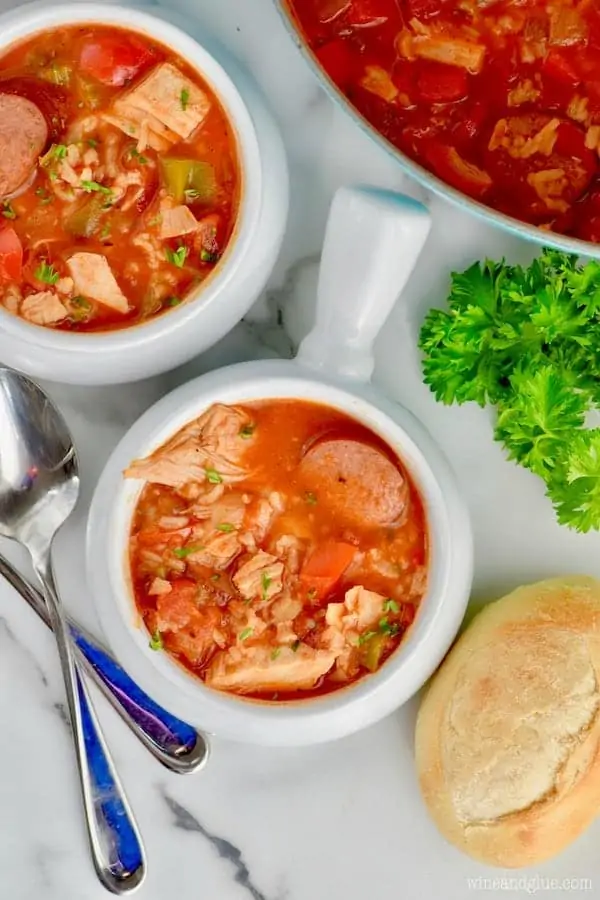 An overhead photo of the Jambalaya Soup with a roll of bread on the side and topped with parsley. 