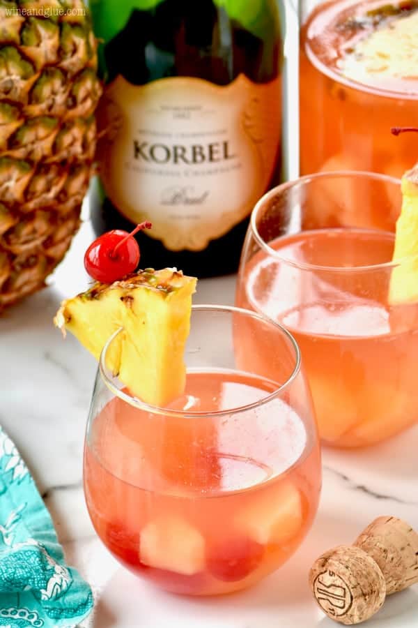 Two glasses of Pina Colada Rum Punch garnished with a slice of pineapple and maraschino cherry. 