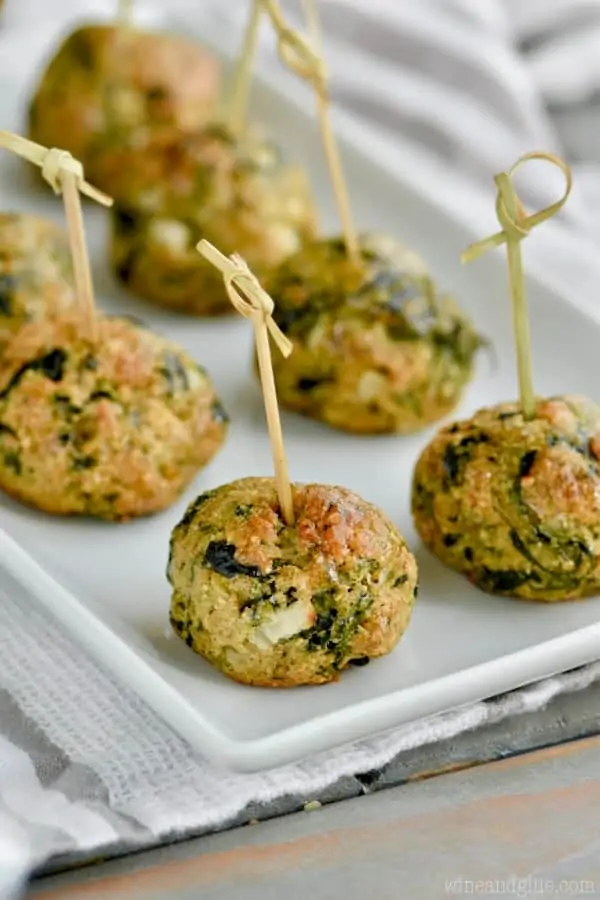 On a white plate and lined up are the Spinach Balls which is a golden brown color. 