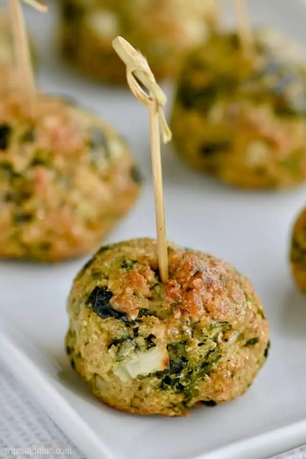 On a white plate and lined up are the Spinach Balls which is a golden brown color. 